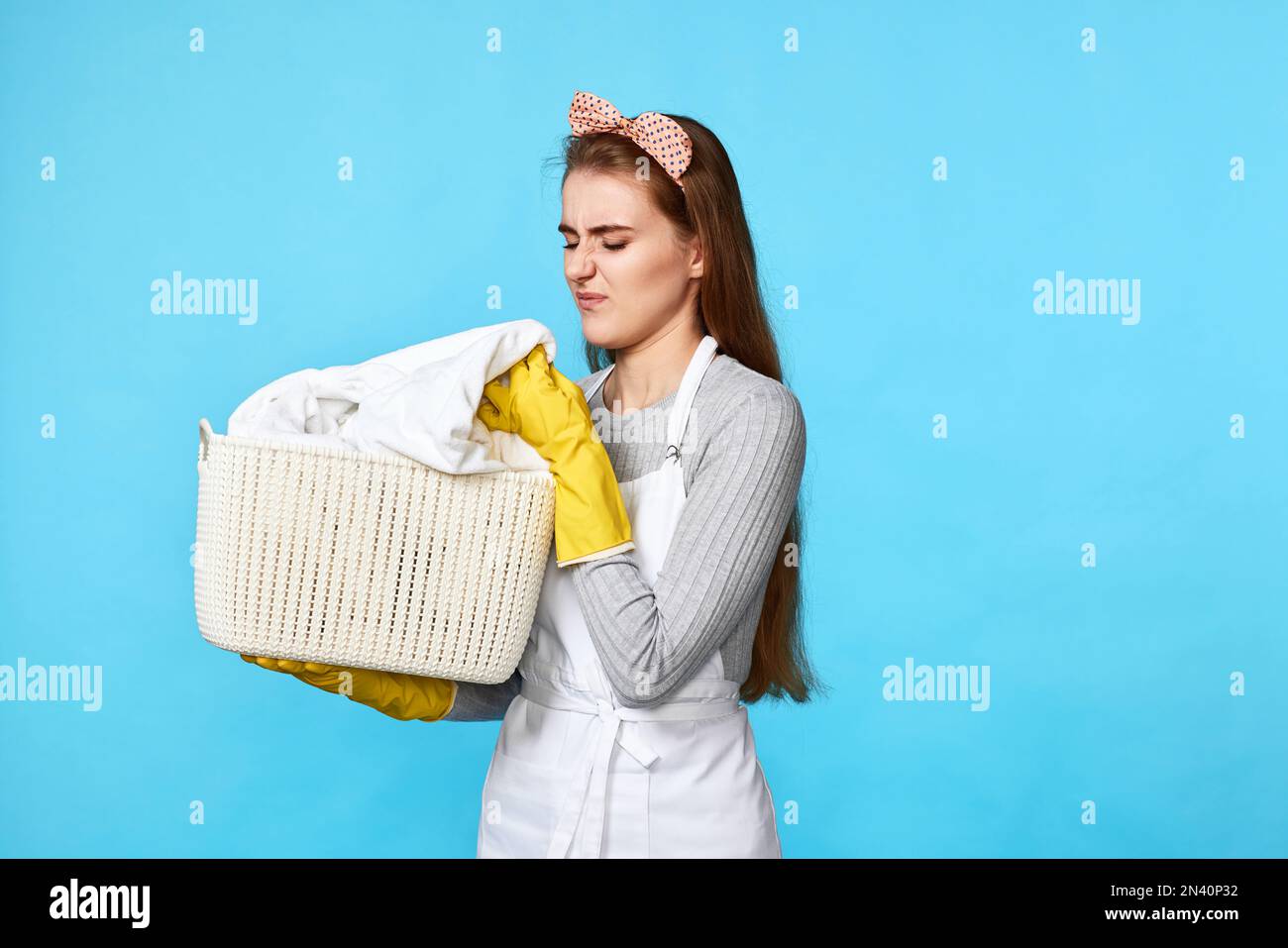 donna caucasica in guanti di gomma che odorano lavanderia su Foto Stock