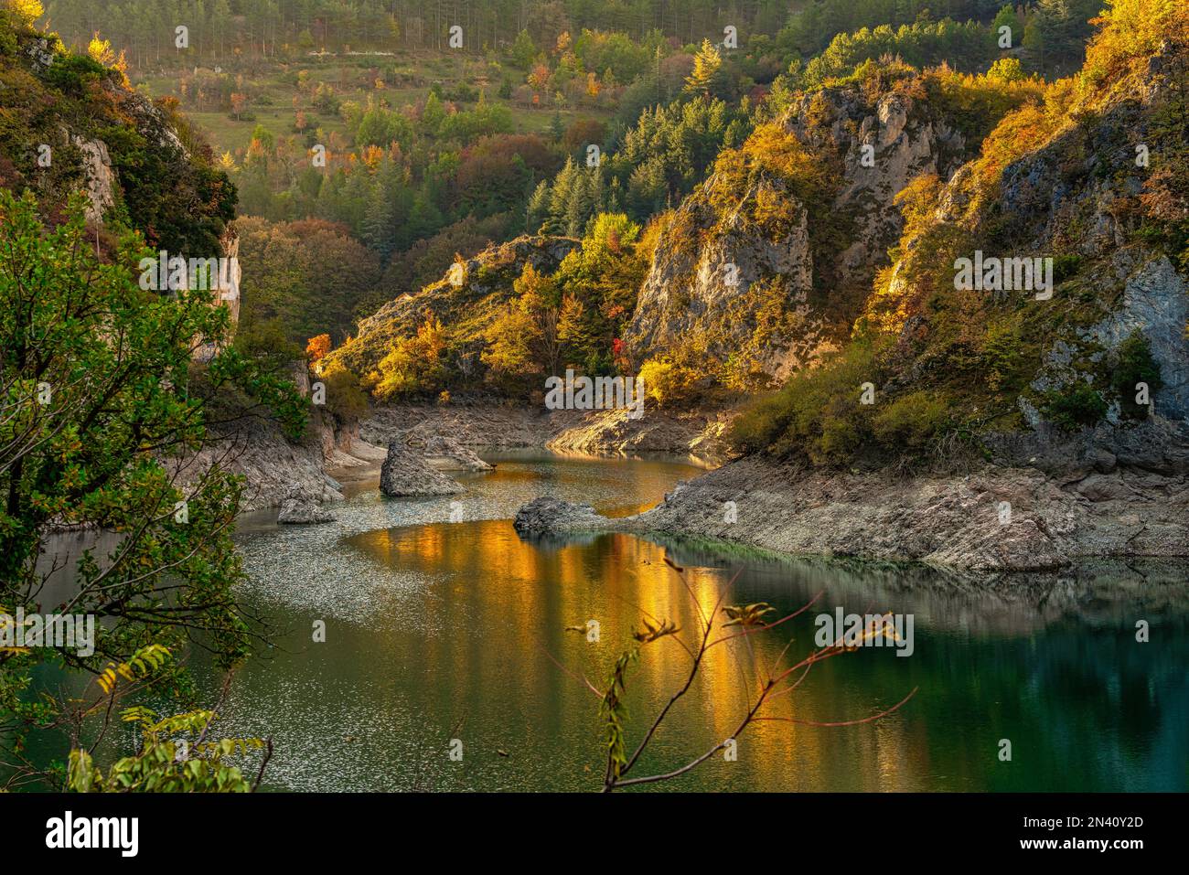 Gli alberi di colore autunnale si riflettono nella piccola acqua del lago di San Domenico illuminata dalla calda luce del tramonto. Abruzzo, Italia, Europ Foto Stock