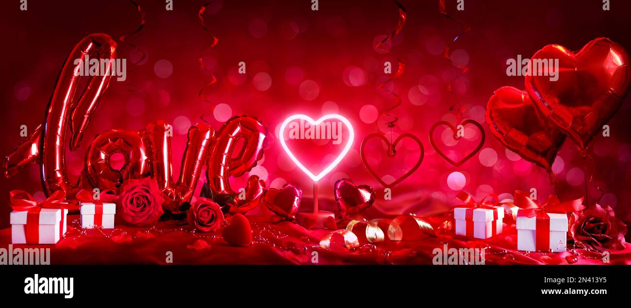 Regalo e Amore di San Valentino - Decorazioni rosse con regali e palloncini rossi in sfondo sfocato astratto Foto Stock
