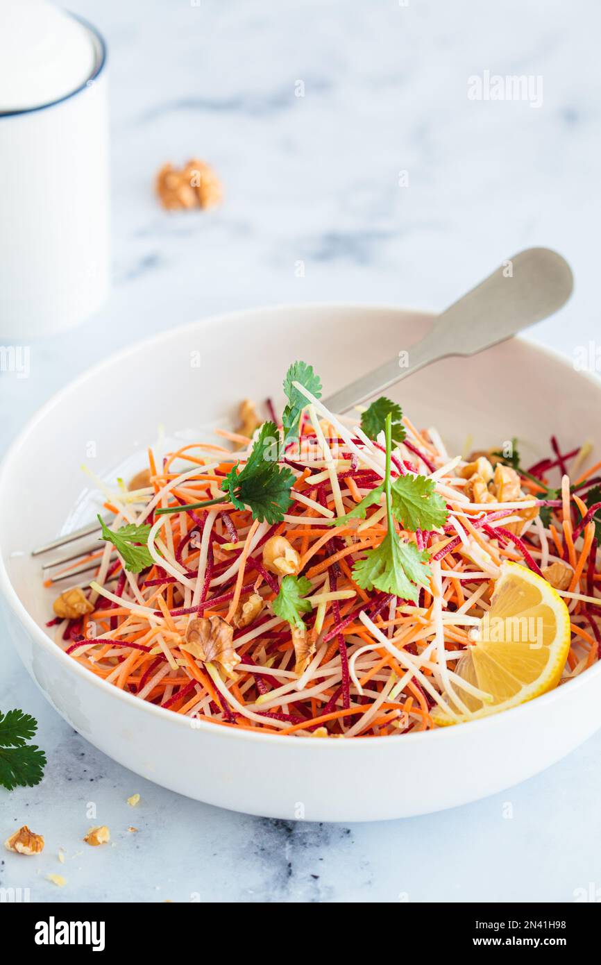 Carote primaverili, barbabietole, insalata di cavolo con noci ed erbe in un recipiente bianco. Foto Stock