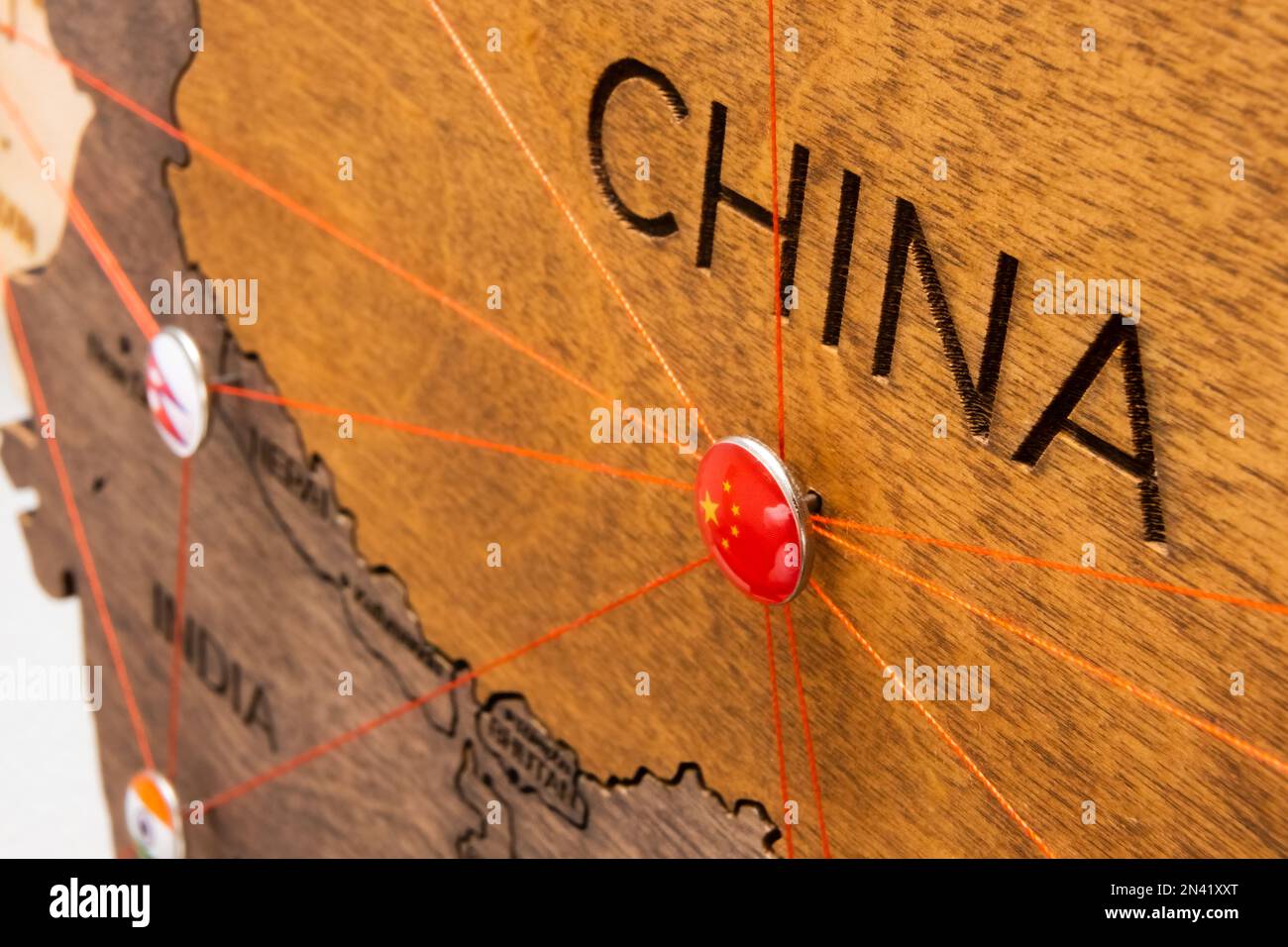 Bandiera cinese sul pushpin e filo rosso sulla mappa di legno, primo piano. Marchio di luoghi da visitare e pianificazione di itinerari di vacanza e di viaggio. Foto Stock