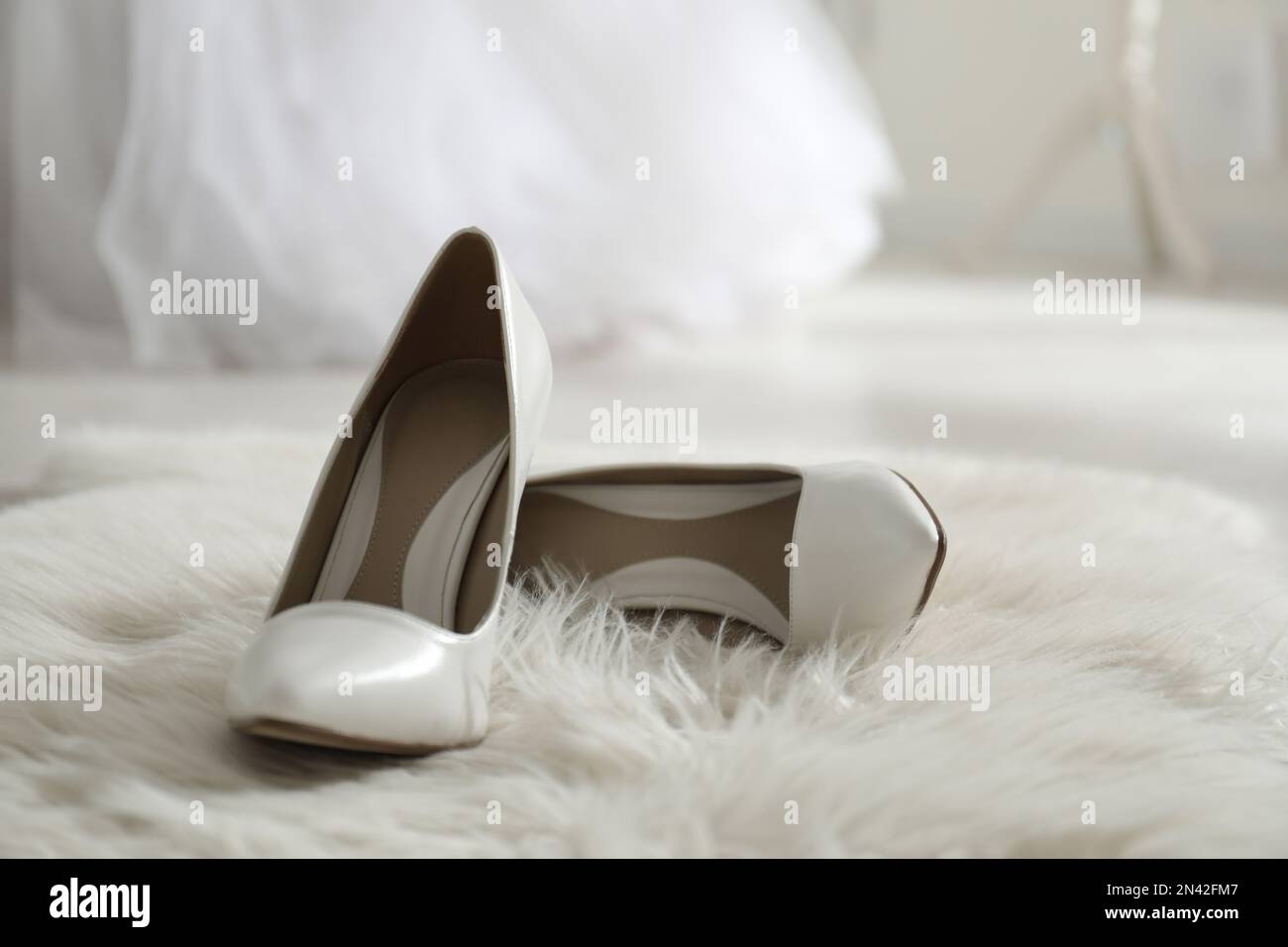 Scarpe bianche da sposa sul tappeto di pelliccia in camera Foto Stock