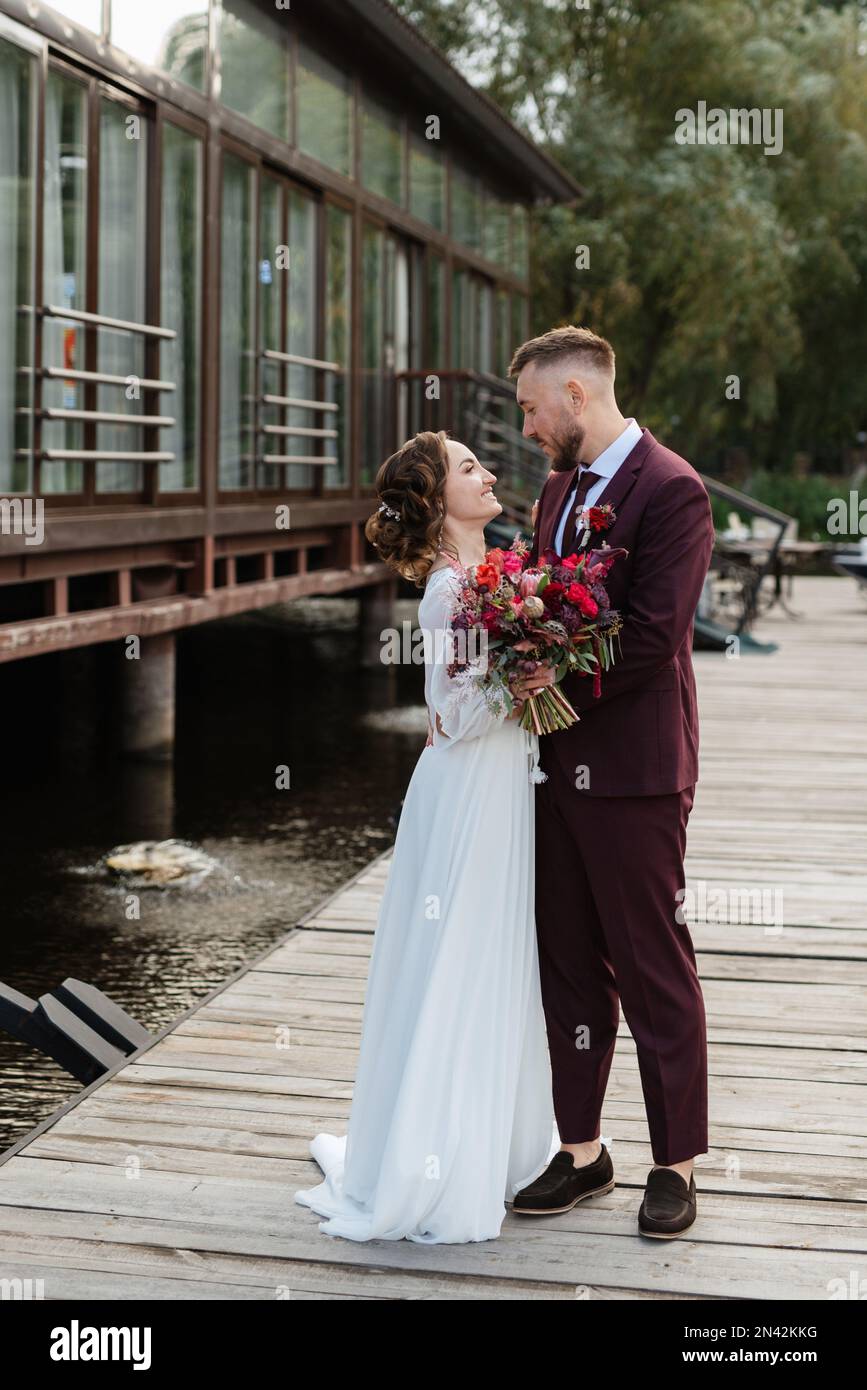 il primo incontro della sposa e dello sposo in abiti da sposa sul molo  vicino all'acqua Foto stock - Alamy