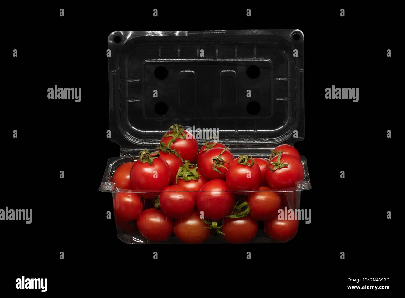 Immagine di pomodori piccoli in confezioni di plastica su sfondo nero Foto Stock