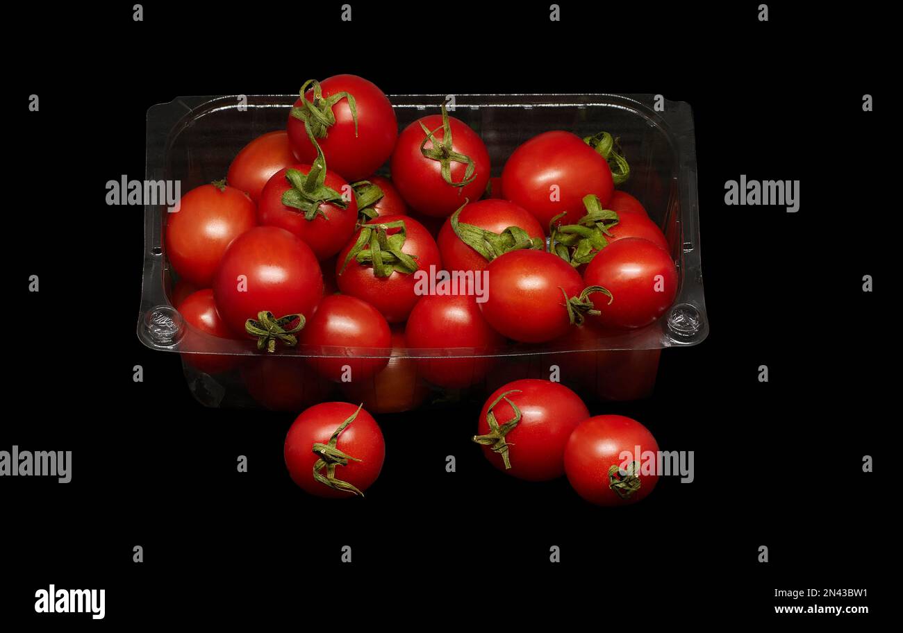 Immagine di pomodori piccoli in confezioni di plastica su sfondo nero Foto Stock