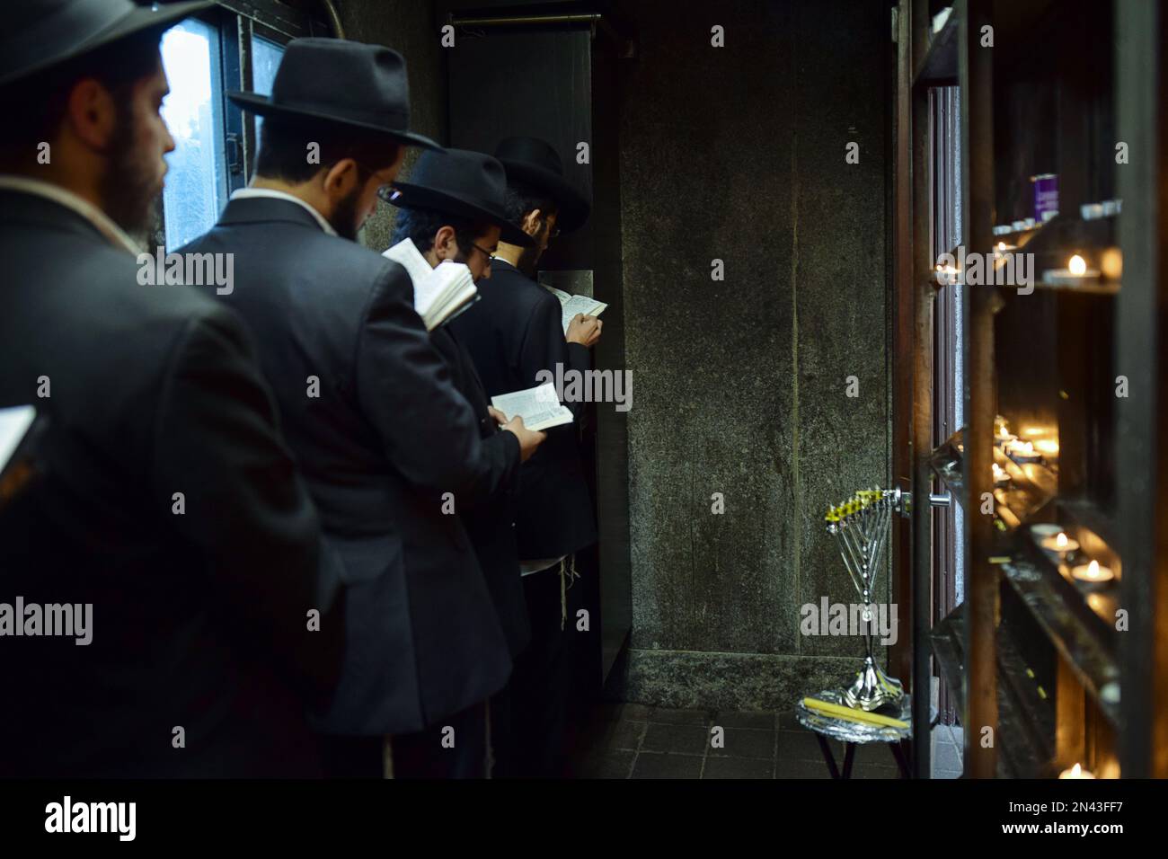 Preghiere dopo l'illuminazione di un menorah Chanukkah in una piccola stanza presso l'Ohel, adiacente alle lapidi degli ultimi 2 Rebbes Lubavitcher. Nel Queens, New York. Foto Stock