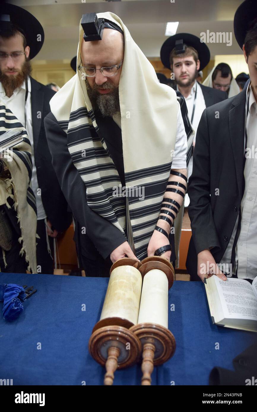 Un uomo ebraico ortodosso è chiamato alla Torah e fa la sua benedizione guardando via per mostrare la sua preghiera a Dio, non alla Torah. A Brooklyn, New York. Foto Stock