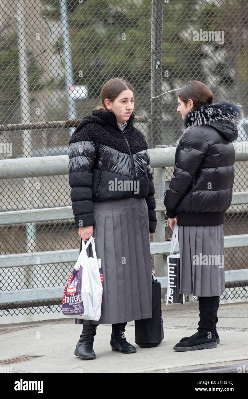 2 ragazze ebree ortodosse vestite modestamente hanno una conversazione. Le gonne pieghettate corrispondenti sono uniformi scolastiche.a brooklyn, New York. Foto Stock