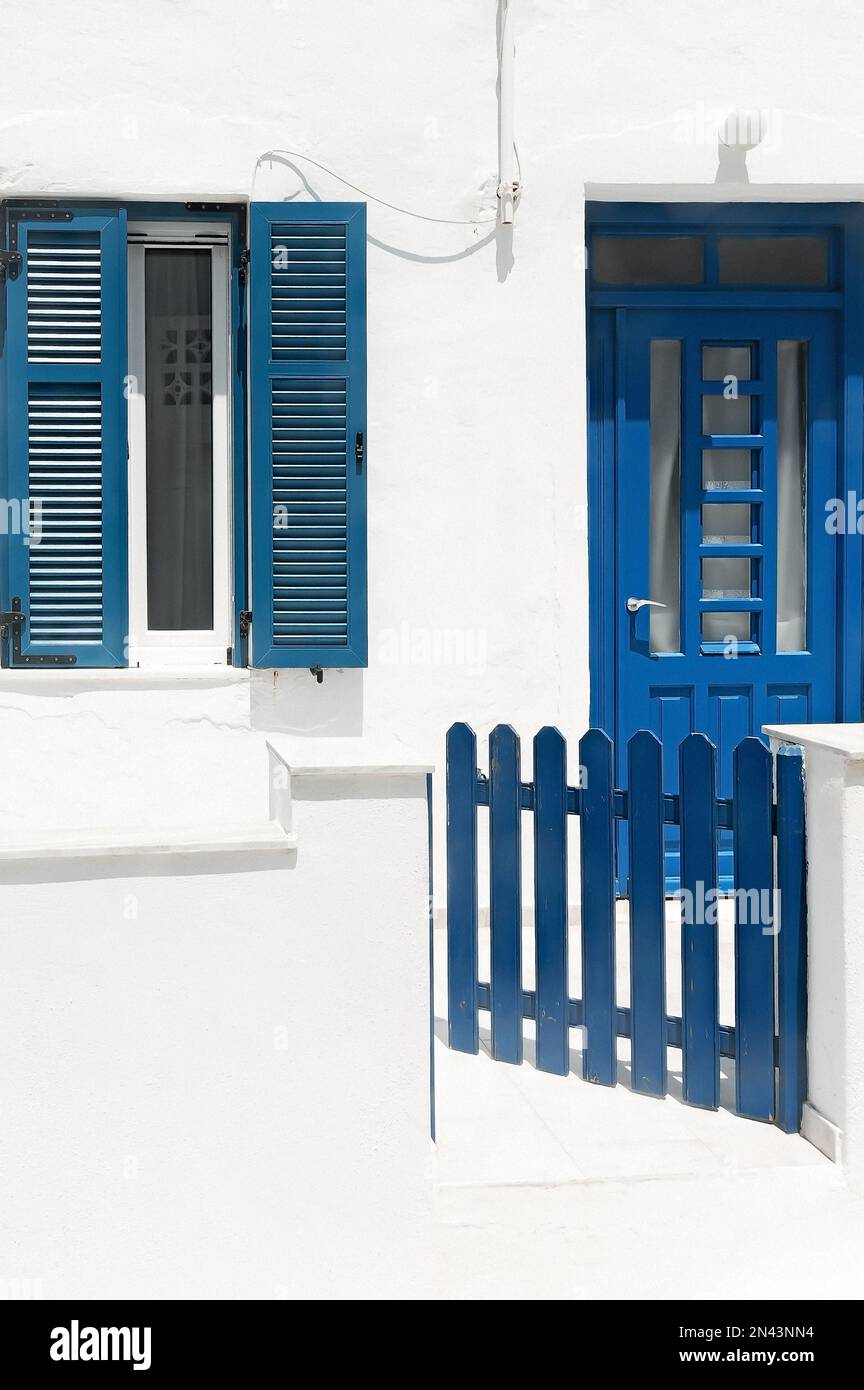 Muro imbiancato con porta blu, finestra e recinzione, stile greco cicladico, Lefkes, Paros, Grecia Foto Stock