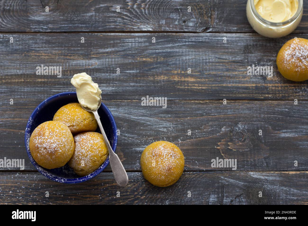 Panini di cardamomo di zucca freschi fatti in casa senza lievito con panna cosparsa di zucchero a velo su asse di legno, stile rustico, piatto Foto Stock