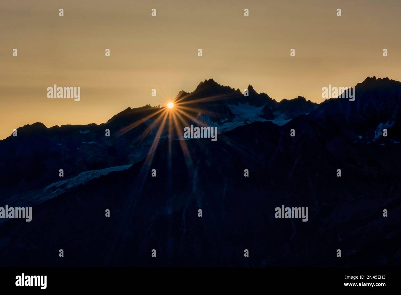 Alto paesaggio alpino con montagne e creste dell'Auvergne-Rhône-Alpes, il sole che sorge vicino alla cima dell'Aiguille du Tour, visto da le Brevent. Foto Stock