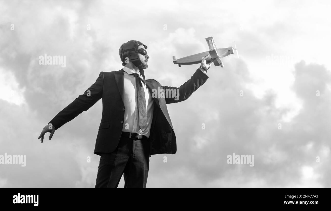 uomo d'affari in abito e cappello pilota lancia giocattolo aereo su sfondo cielo. aspirazioni Foto Stock