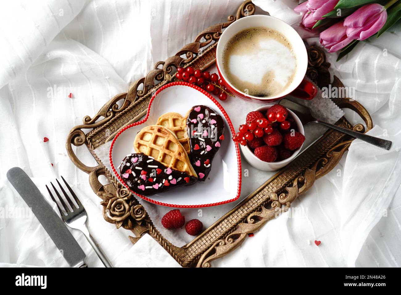 San Valentino colazione in camera a forma di cuore waffle cappuccino lamponi serviti in vassoio Foto Stock