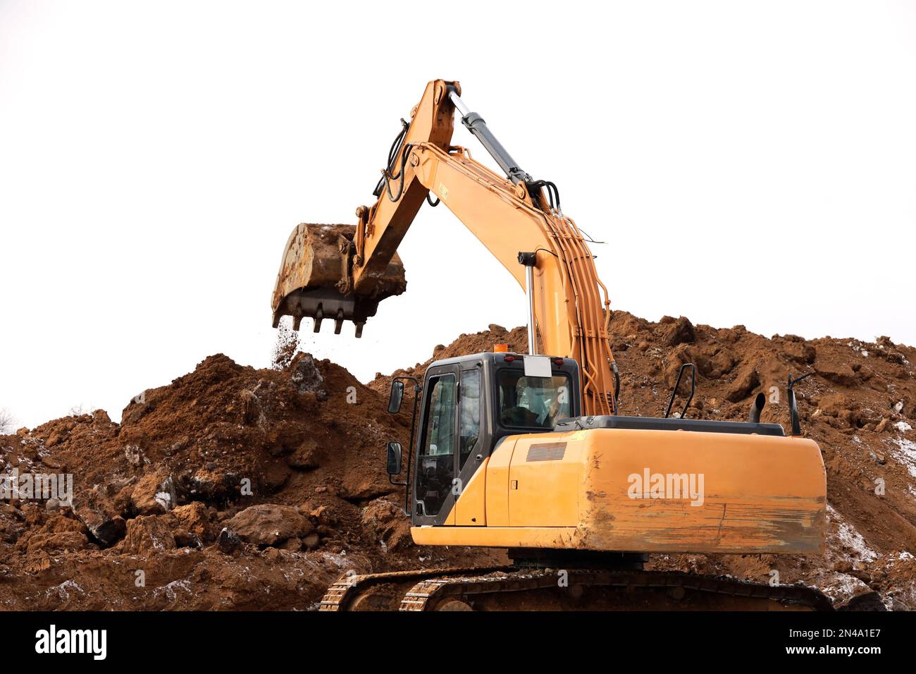 L'escavatore cingolato scarta il terreno con una benna. Lavori di movimento terra, scavo in cantiere Foto Stock