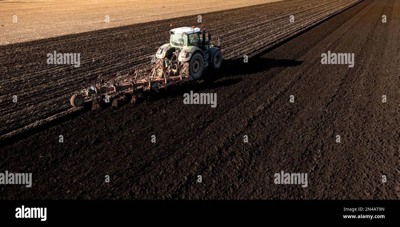 Una vista aerea di un trattore che arava un fertile campo agricolo con una ricca terra scura per colture e produzione alimentare con spazio di copia Foto Stock