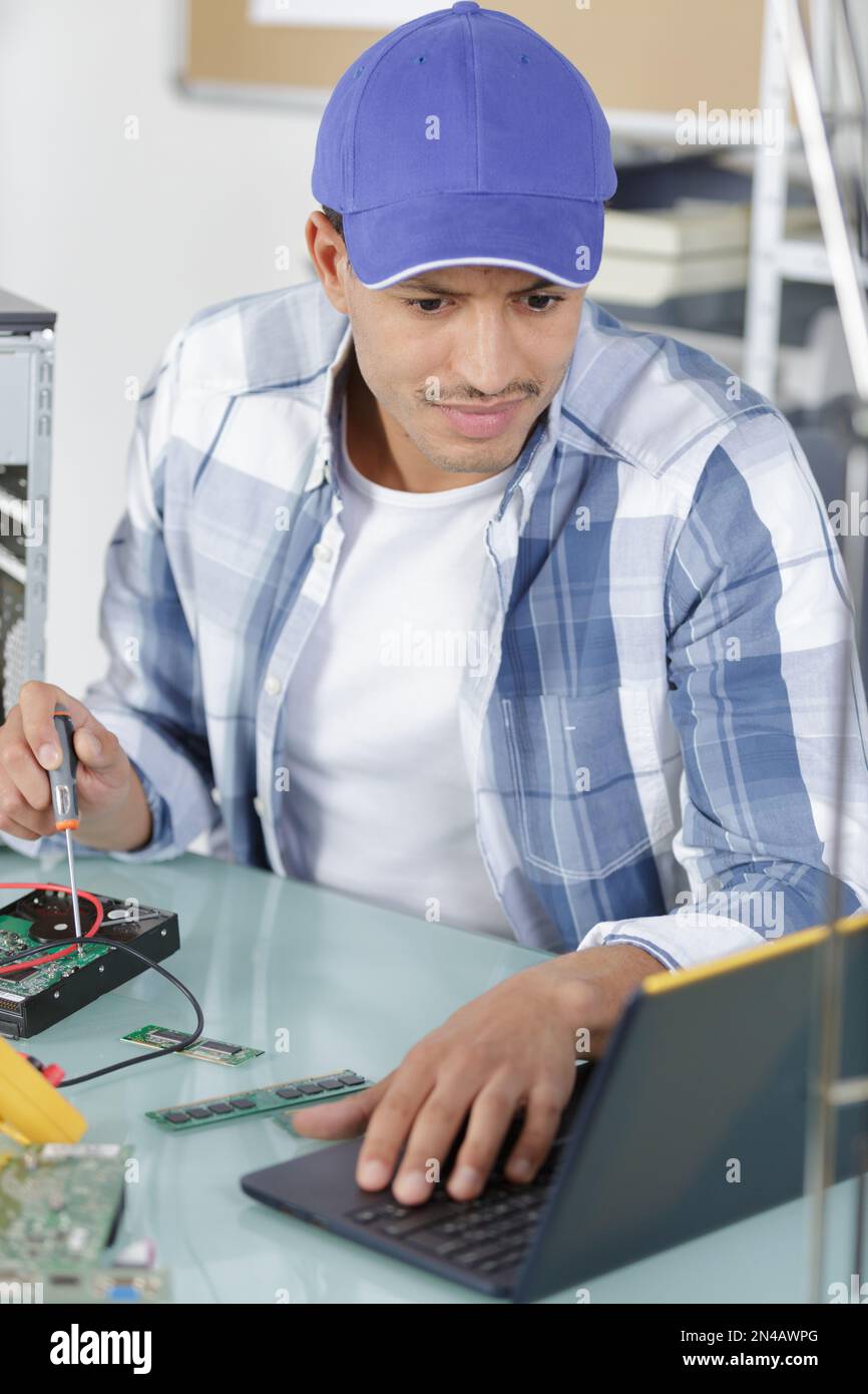 uomo che utilizza un notebook per riparare un pc Foto Stock