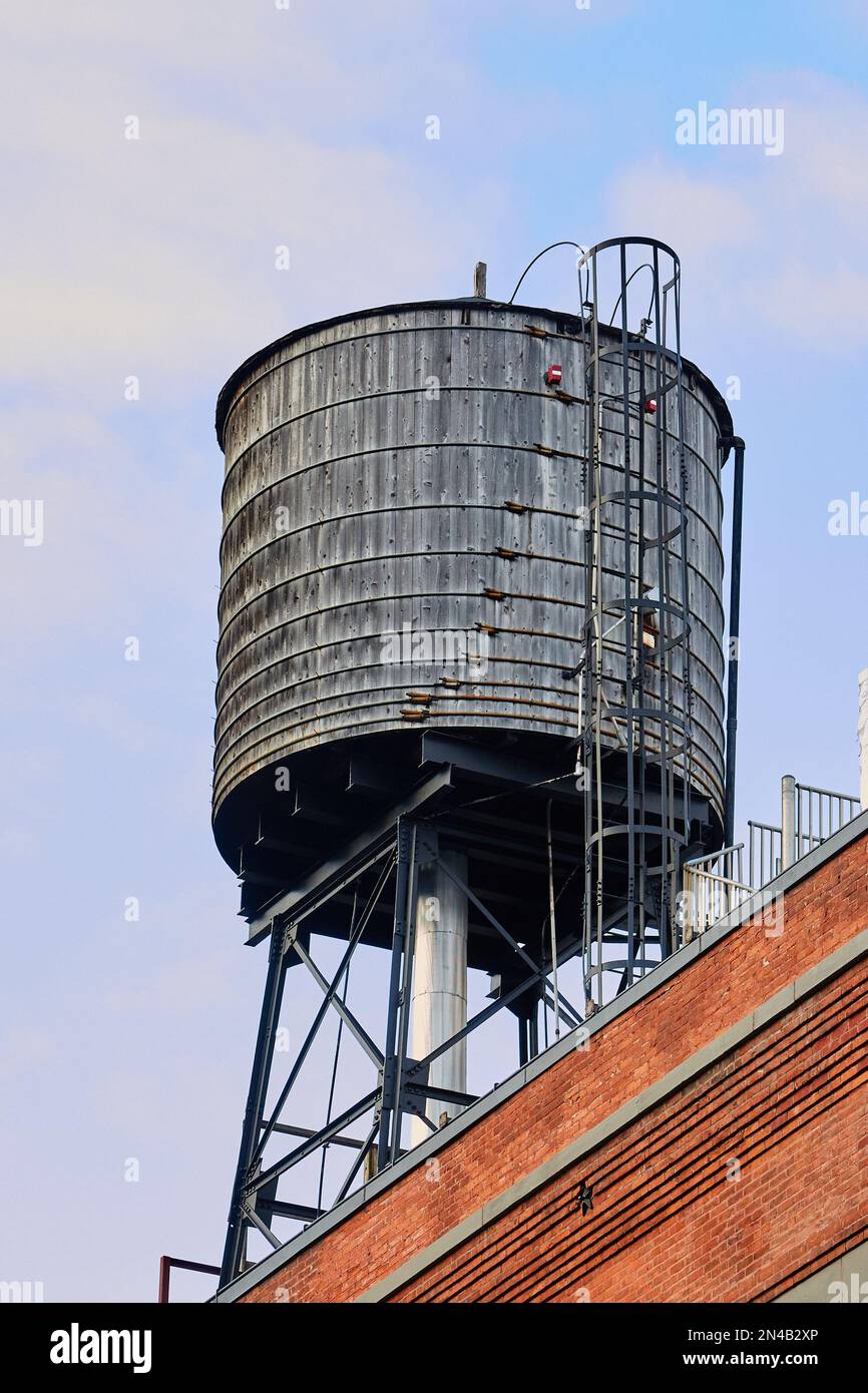 Grey Water Tower con scala sul Red Brick Building di NYC Foto Stock