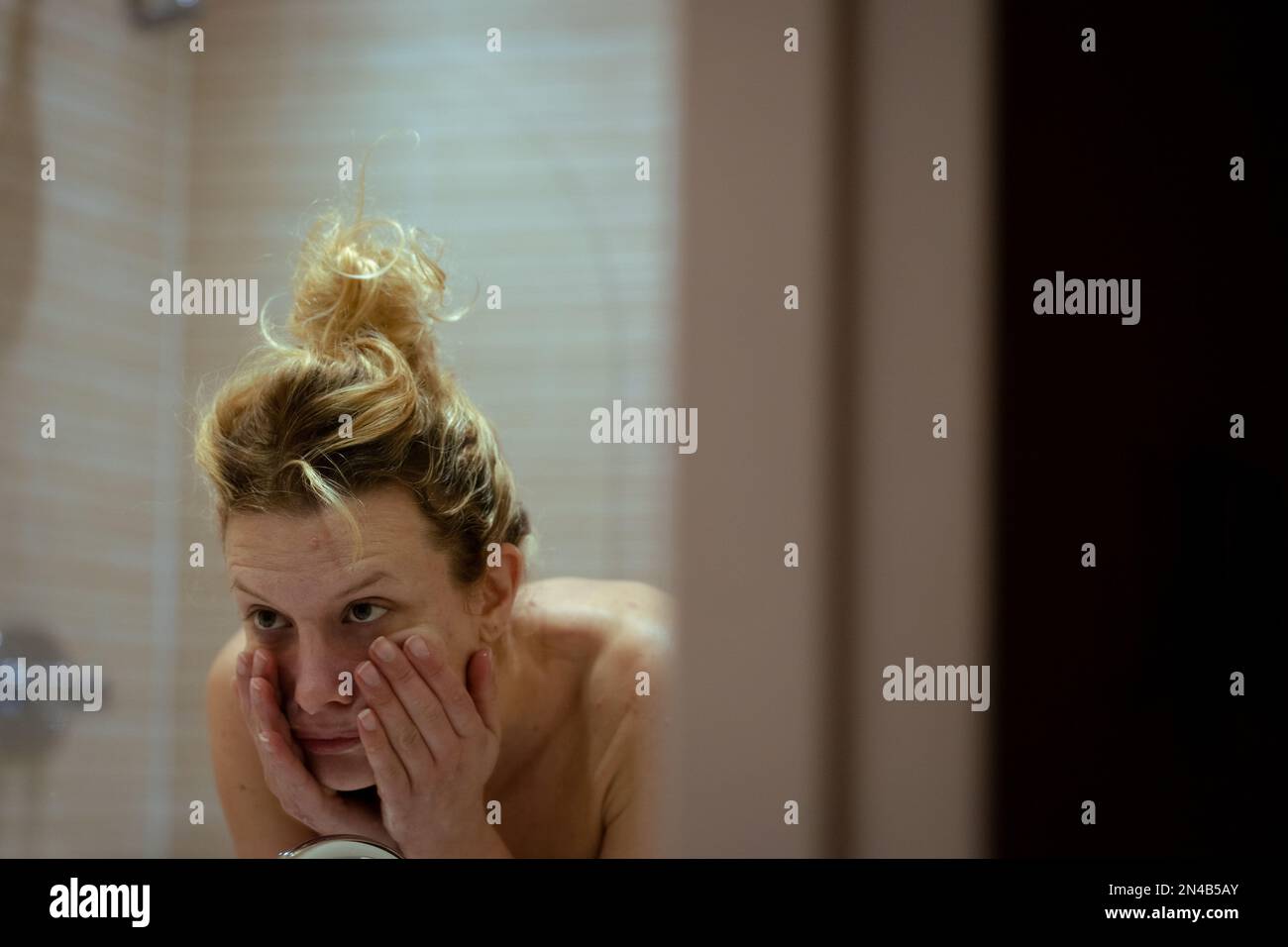 Giovane donna che pulisce il viso in bagno, cura della pelle routine Foto Stock