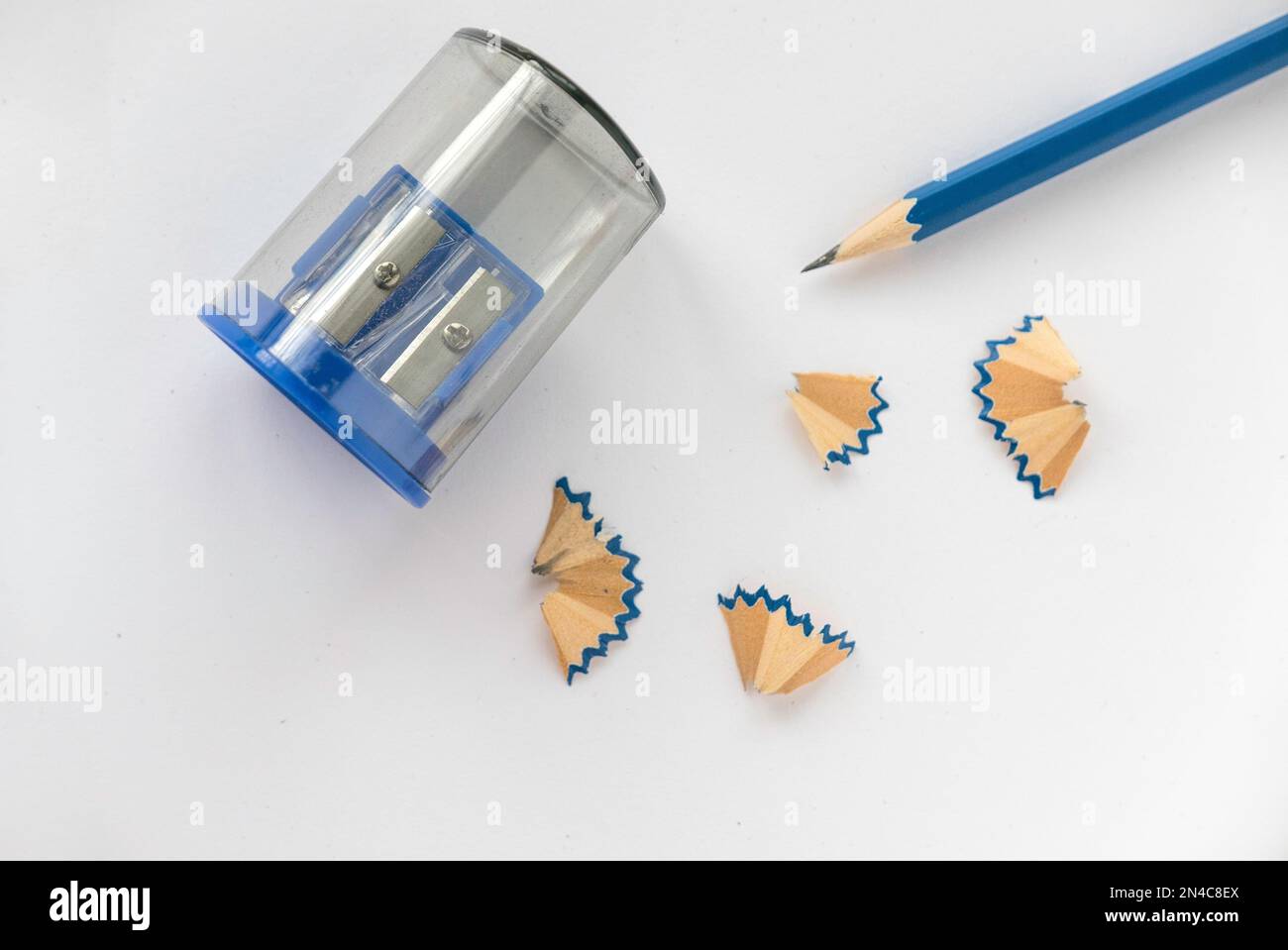 Matita blu con affilatrice a matita e le sue schegge su sfondo bianco. Foto Stock