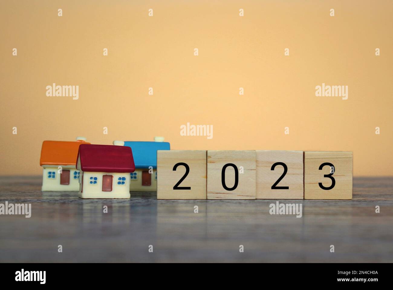 Blocchi di legno con il numero 2023 e casa. Previsione dei prezzi immobiliari, tendenze e cambiamenti, nuove sfide per l'economia e l'impatto sugli alloggi Foto Stock