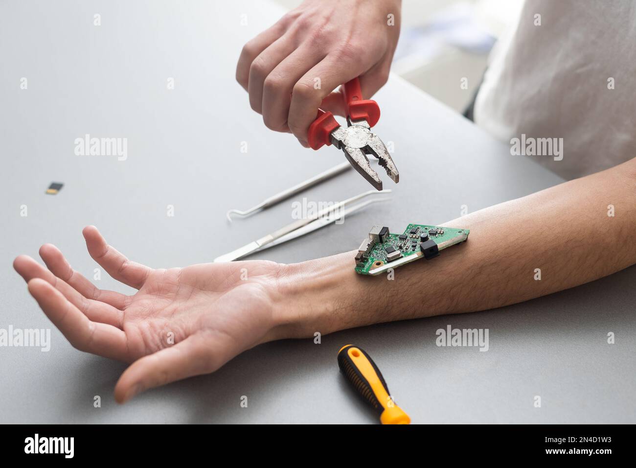 Concetto del braccio del robot. L'uomo mostra una mano biomeccanica protesica. Guy ripara la mano con l'attrezzo. Bioingegneria, transumanesimo, biohacking, cyborg umano Foto Stock
