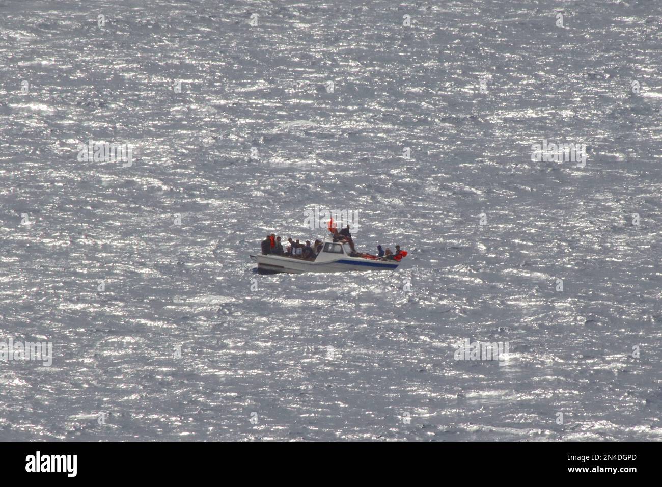 Gli algerini maschi migranti agitano giubbotti di salvataggio per attirare l'attenzione, avendo perso il potere sulla loro barca mentre si sposta nel Mar Mediterraneo, 2022 agosto. Foto Stock