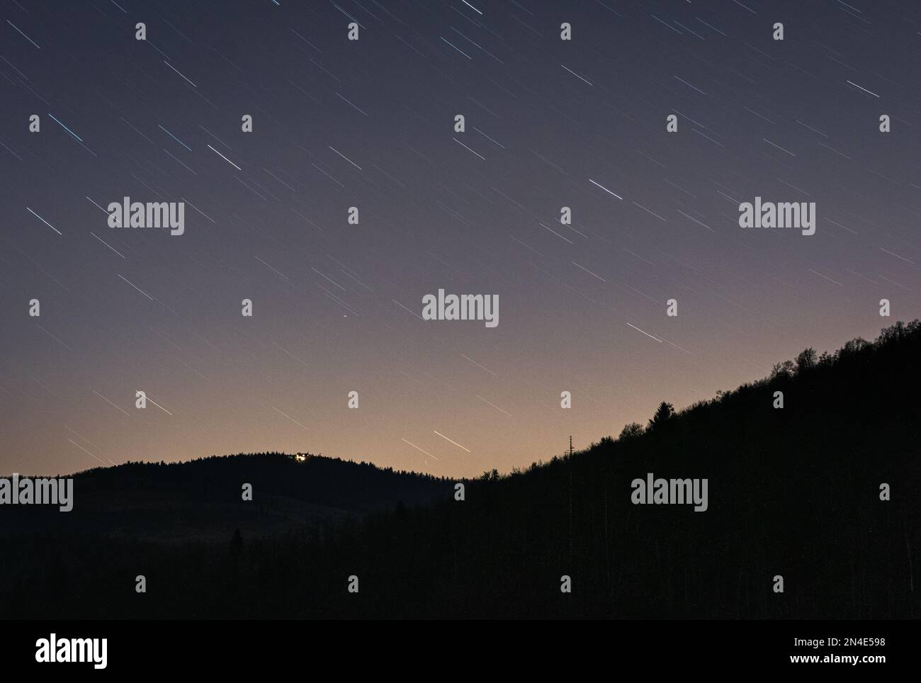 L'illusione di stelle cadenti nel cielo notturno e uno skyline di colline Foto Stock