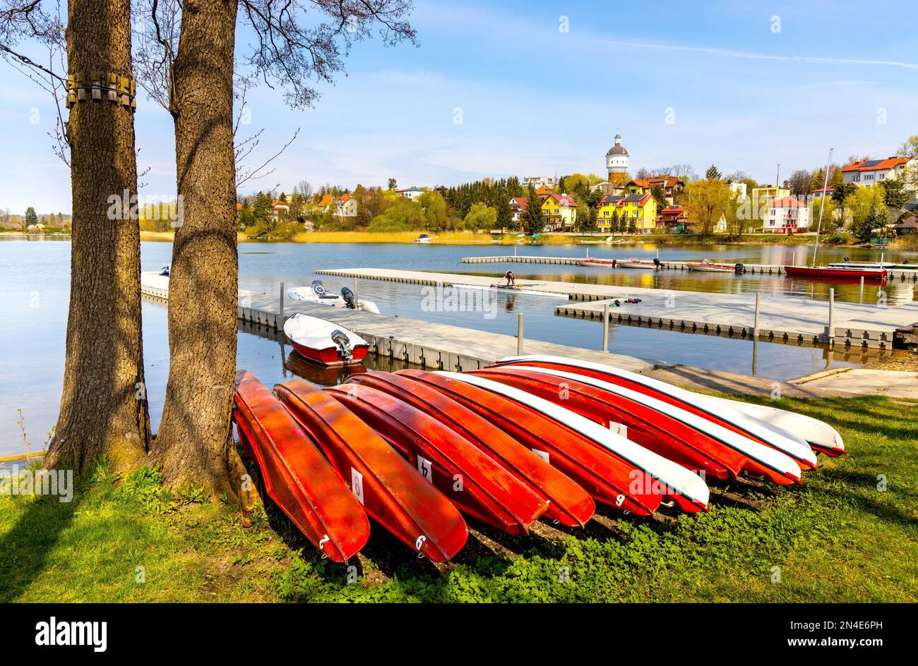 Elk, Polonia - 1 maggio 2022: Centro ricreativo per sport acquatici MOSIR con barche al lago Jezioro Elckie con litorale, torre d'acqua e centro città di Elk a M. Foto Stock