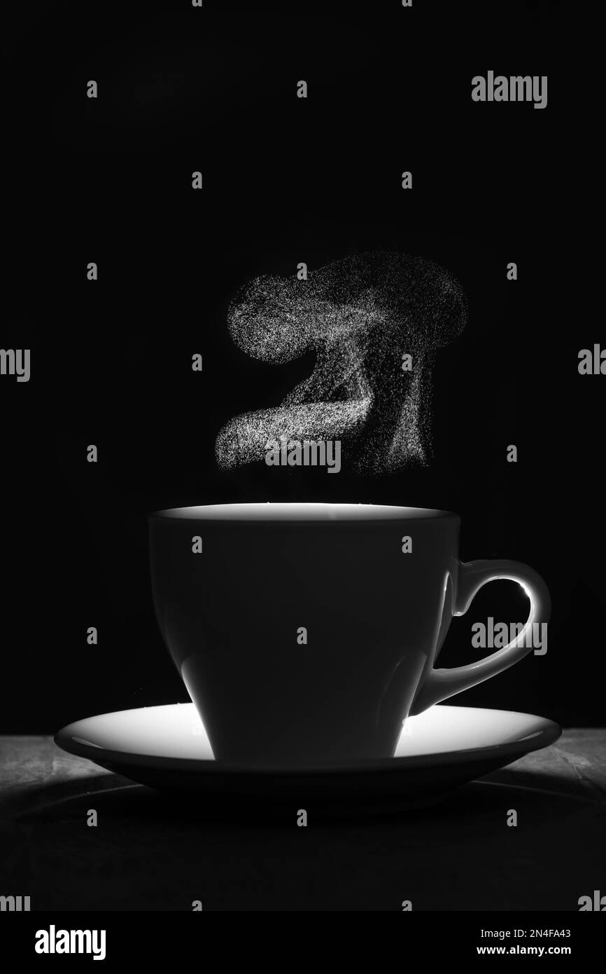 Silhouette di una tazza con una bevanda calda e un elegante vapore riccio che si innalza. Una tazza di caffè fumante su sfondo nero. Caffè mattutino. Foto Stock