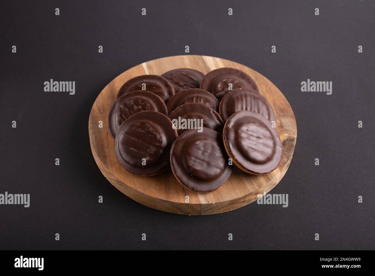 biscotti con scaglie di cioccolato giacenti su un asse di legno su uno sfondo nero Foto Stock
