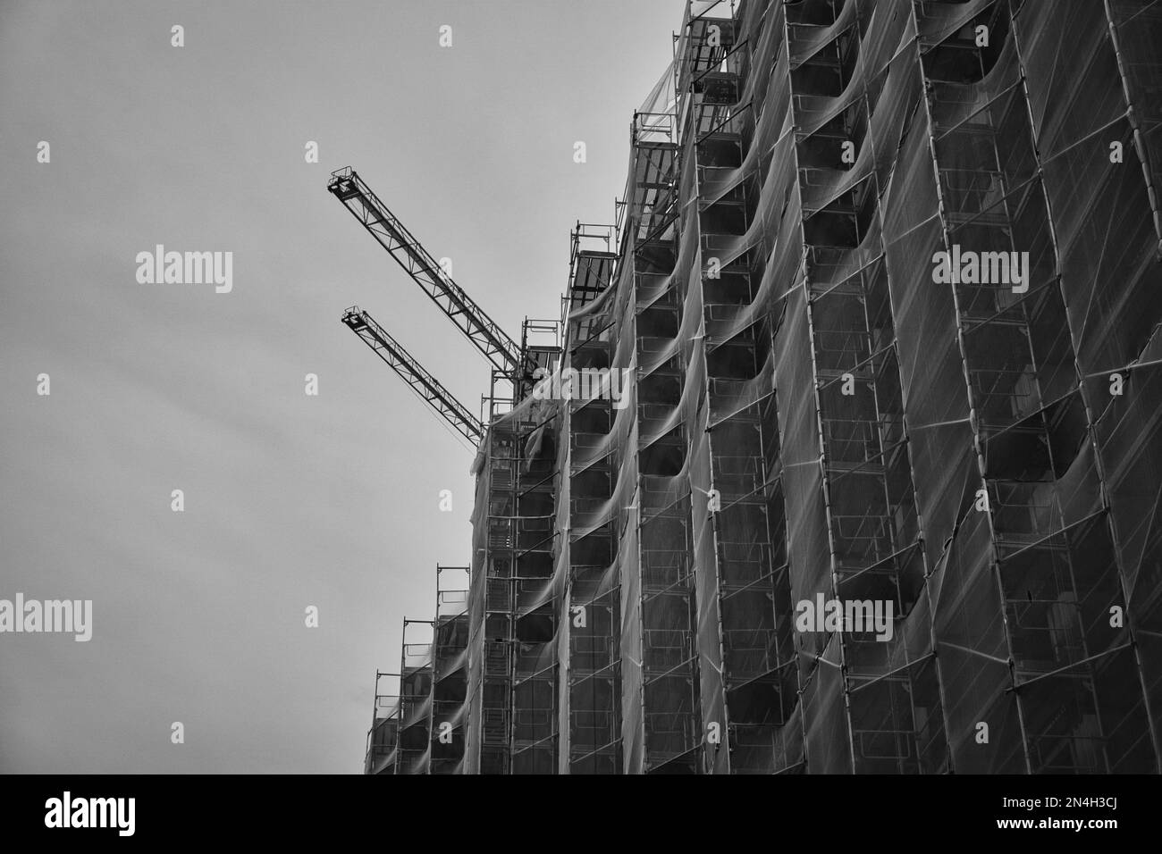 Una scala di grigi di una rete di sicurezza in un edificio di appartamenti durante la costruzione Foto Stock