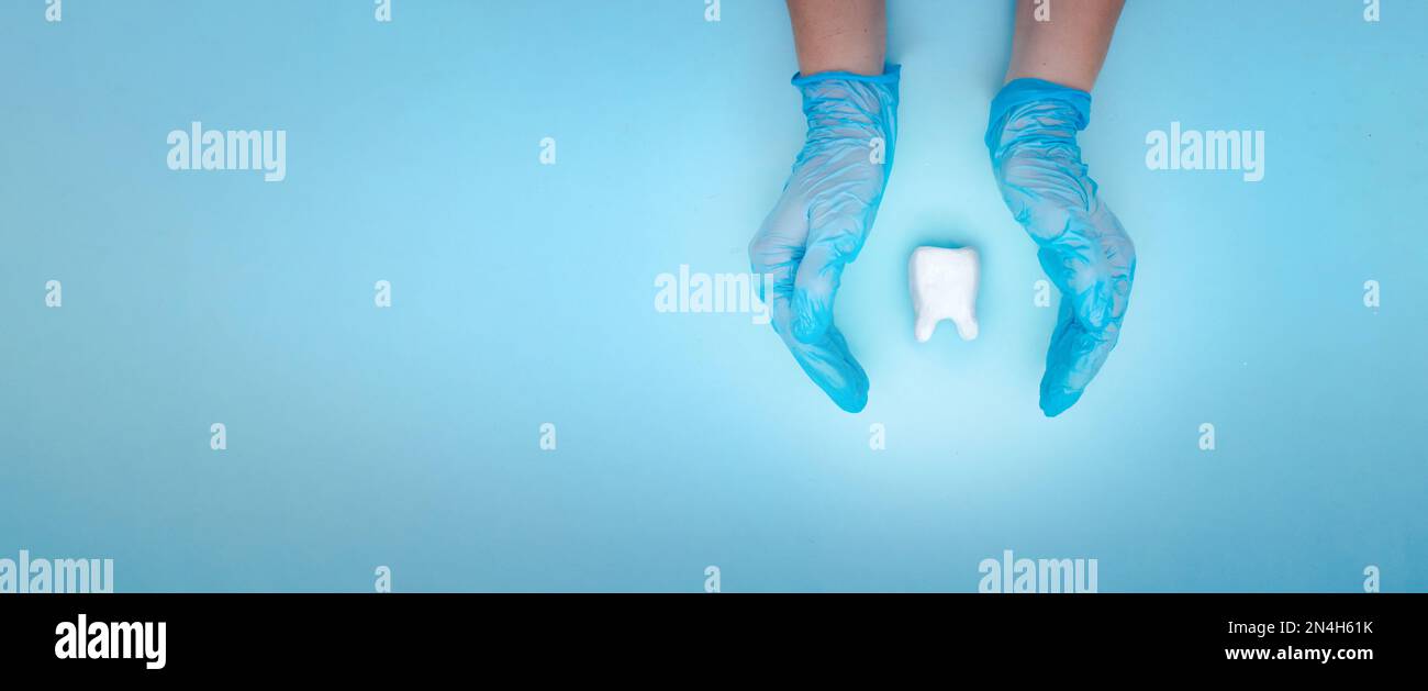 Donna che tiene il dente bianco su sfondo blu pastello. Concetto medico di stomatologia del dentista Foto Stock