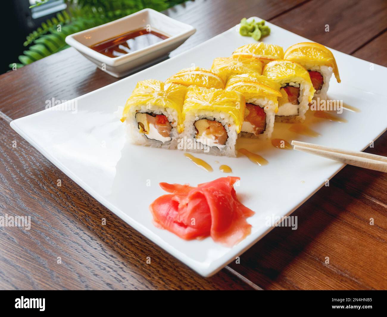 Involtini con riso, nori di alghe, salmone, formaggio spalmabile, uova di pollo, caviale masago, arancione. Zenzero marinato e salsa wasabi. Cucina asiatica Foto Stock