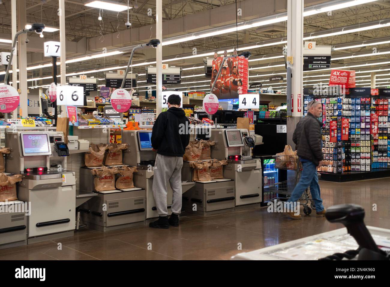 Un acquirente maschio usa una stazione self-checkout mentre un altro uomo cammina vicino a Dillon's Market, Wichita, Kansas, USA. Foto Stock