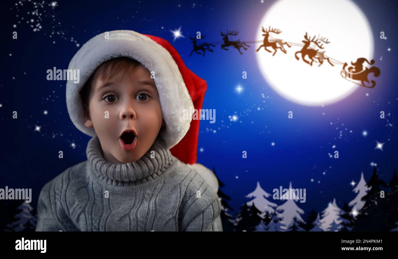 Carino bambino e Babbo Natale volare in slitta contro il cielo della luna sullo sfondo. Festa di Natale Foto Stock