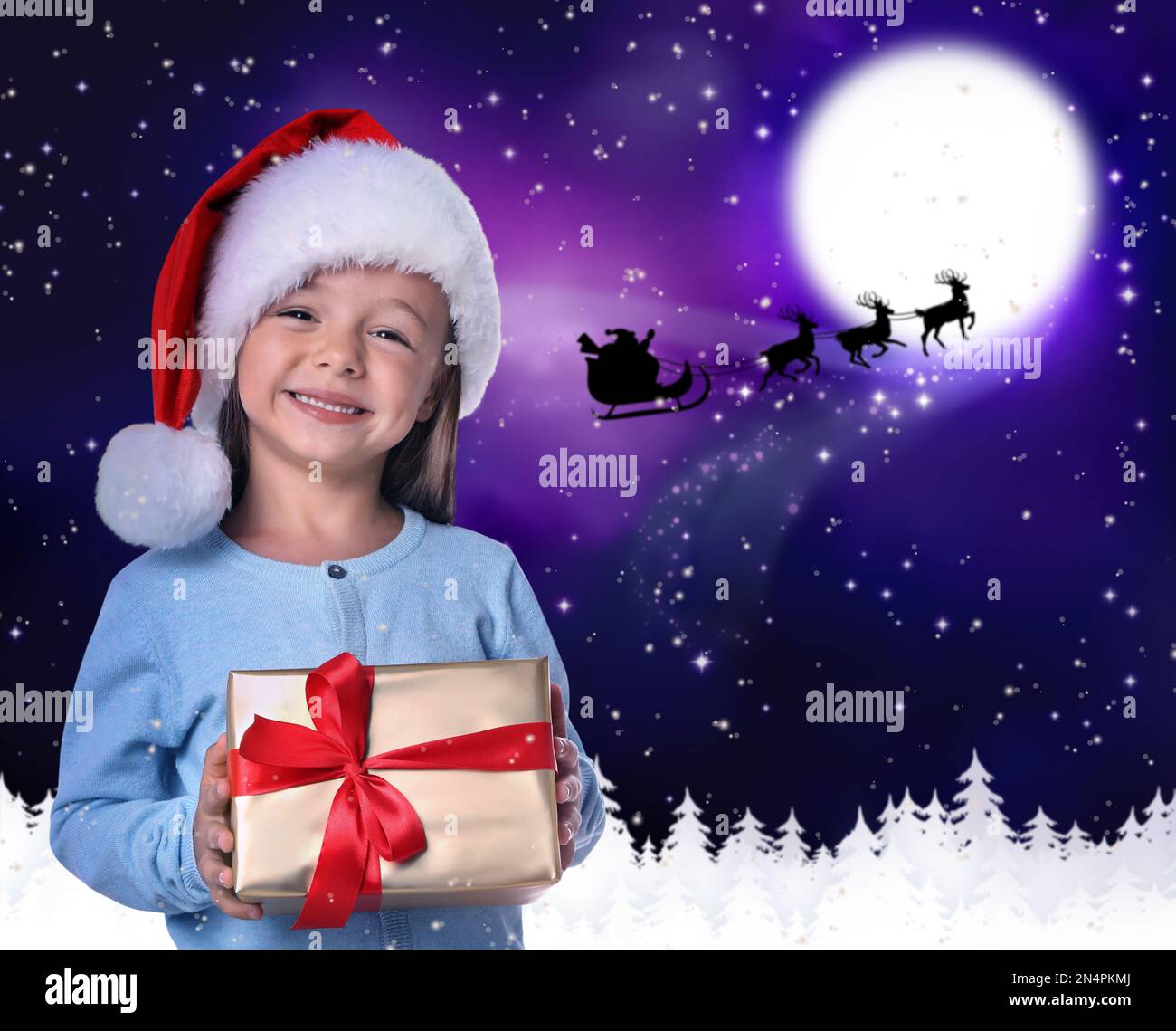 Carino bambino e Babbo Natale volare in slitta contro il cielo della luna sullo sfondo. Festa di Natale Foto Stock