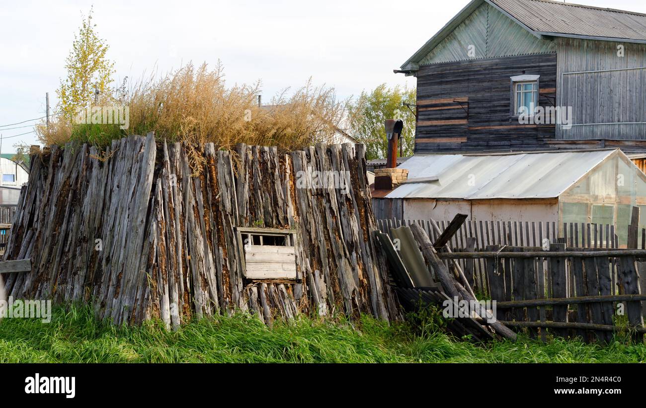 La stanza per il khoton del bestiame, fatta di sterco della mucca e di legno, overgrown con l'erba sta su un terreno con una casa ed una serra nel nord di Yakutia. Foto Stock