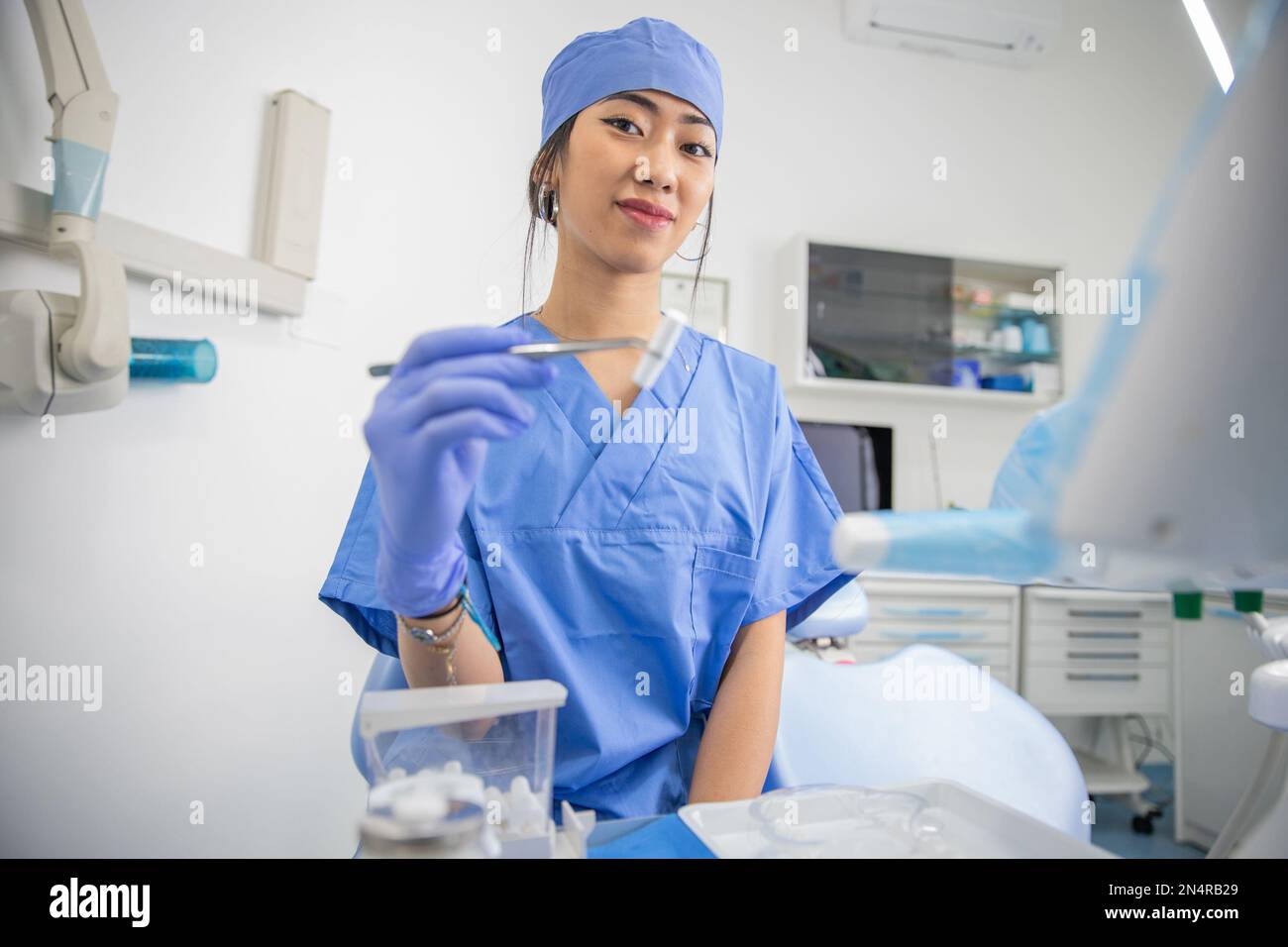 Un dentista asiatico femmina che tiene pinze e garza, operatore sanitario Foto Stock