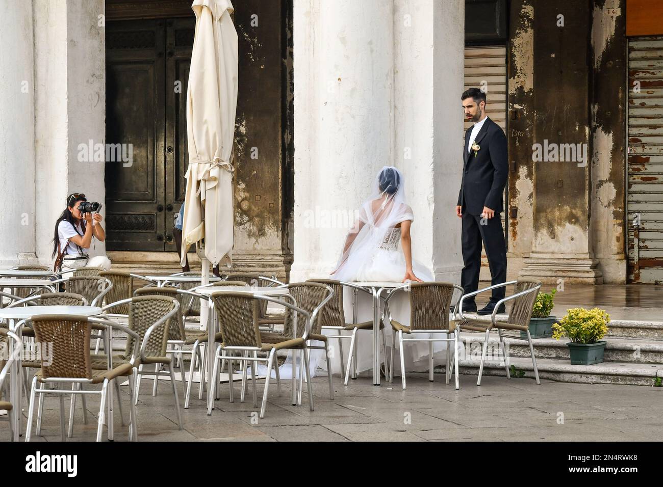 Un professionista che fotografa una coppia appena sposata in un caffè sul marciapiede di Piazza San Marco, Venezia, Veneto, Italia Foto Stock