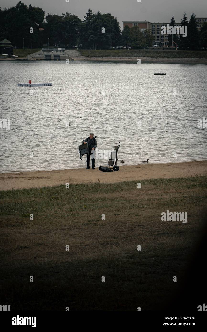 Un colpo verticale di vecchio pescatore che impacca le sue attrezzature sulla riva a Jablonec nad Nisou, Repubblica Ceca Foto Stock