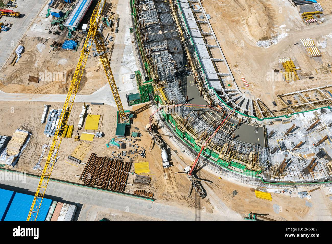cantiere dall'alto. costruttori che versano un calcestruzzo bagnato sul cantiere di costruzione di stadio. vista dall'alto dell'antenna. Foto Stock