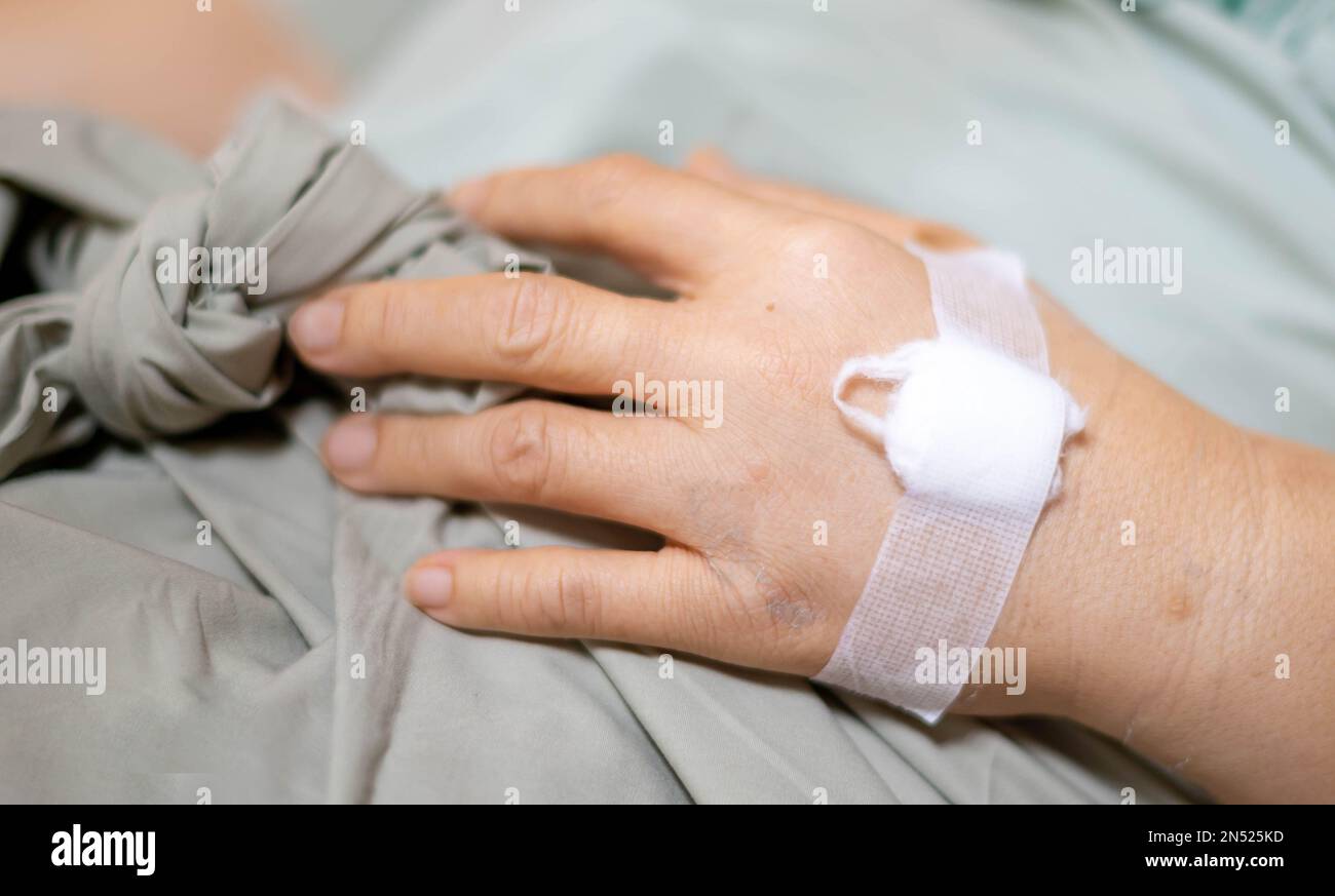 La mano femminile dà una soluzione salina a letto in ospedale. Foto Stock