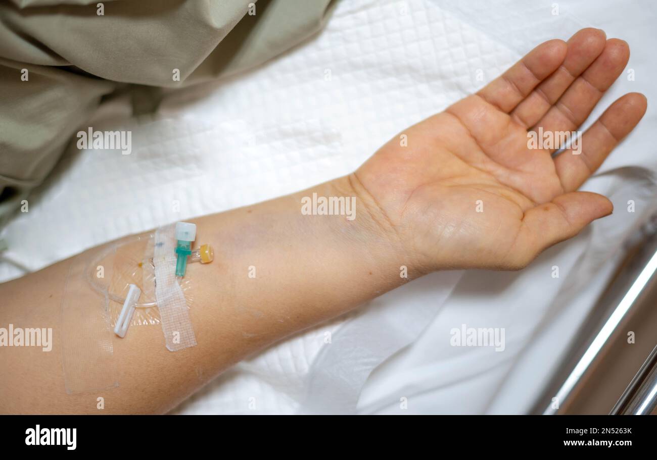 La mano femminile dà una soluzione salina a letto in ospedale. Foto Stock