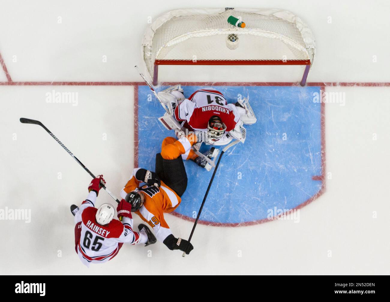 Philadelphia Flyers' Scott Hartnell, center, slides into Carolina Hurricanes goalie Anton Khudobin, top, of Russia, after behing hooked by Hurricanes' Ron Hainsey during the second period of an NHL hockey game, Sunday, April 13, 2014, in Philadelphia. (AP Photo/Chris Szagola) Foto Stock