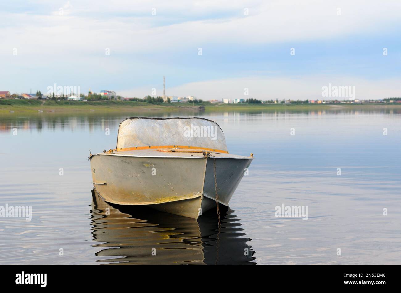 Metallo vecchio la barca è in acqua calma con il riflesso di nuvole incatenate sullo sfondo del Yakut dei villaggi del nord nel suntar foresta. Foto Stock