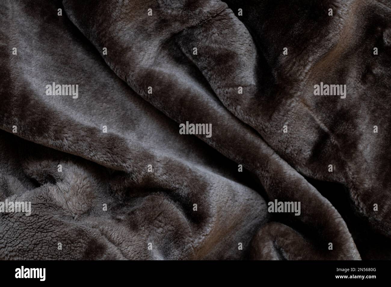 Sfondo di un camice di pelle di pecora nero da uomo in pelliccia sintetica, primo piano di fondo in pelliccia Foto Stock