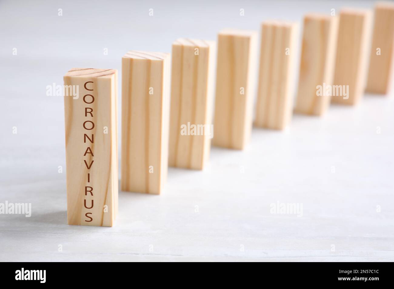 Piastrelle di legno domino su tavolo bianco, spazio per il testo. Diffusione del concetto di coronavirus Foto Stock
