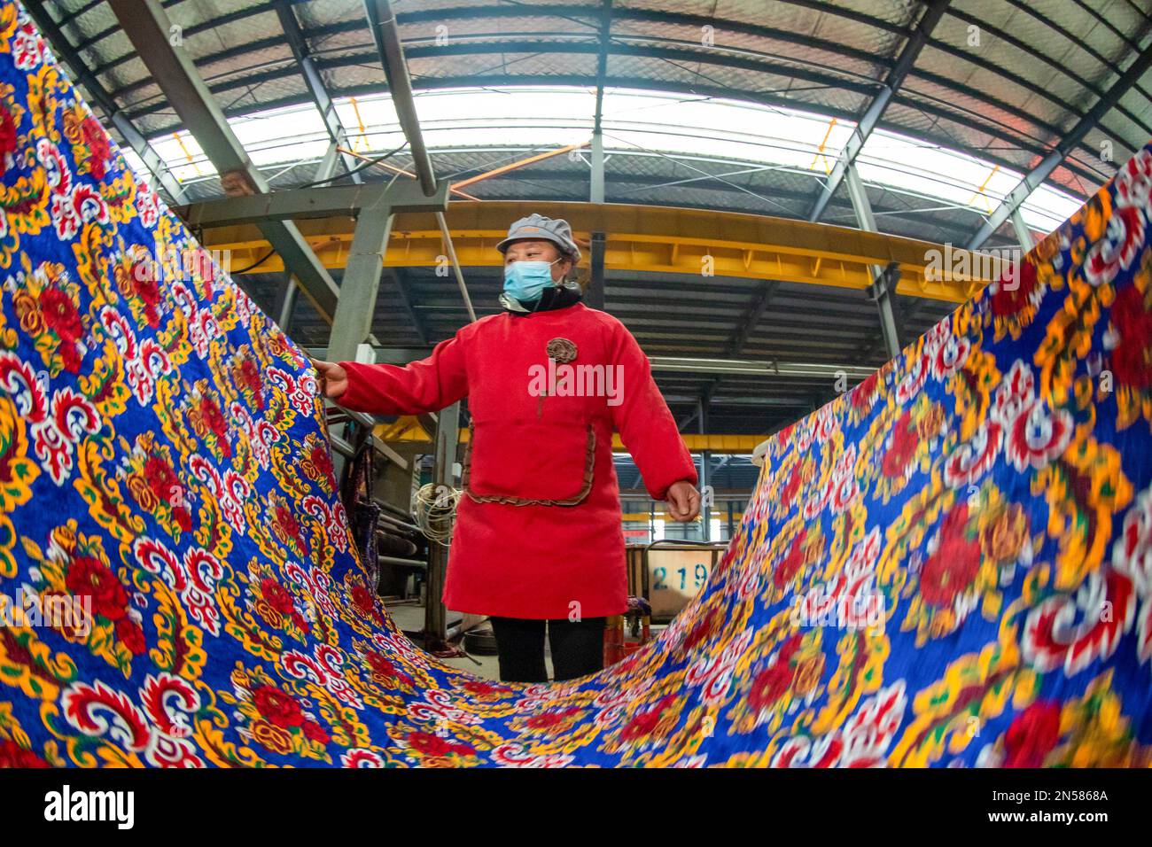 HAI'AN, CINA - 9 FEBBRAIO 2023 - Un lavoratore produce tessuti tessili per l'esportazione su una linea di produzione presso il laboratorio di produzione di Nantong Leyida Textile Foto Stock