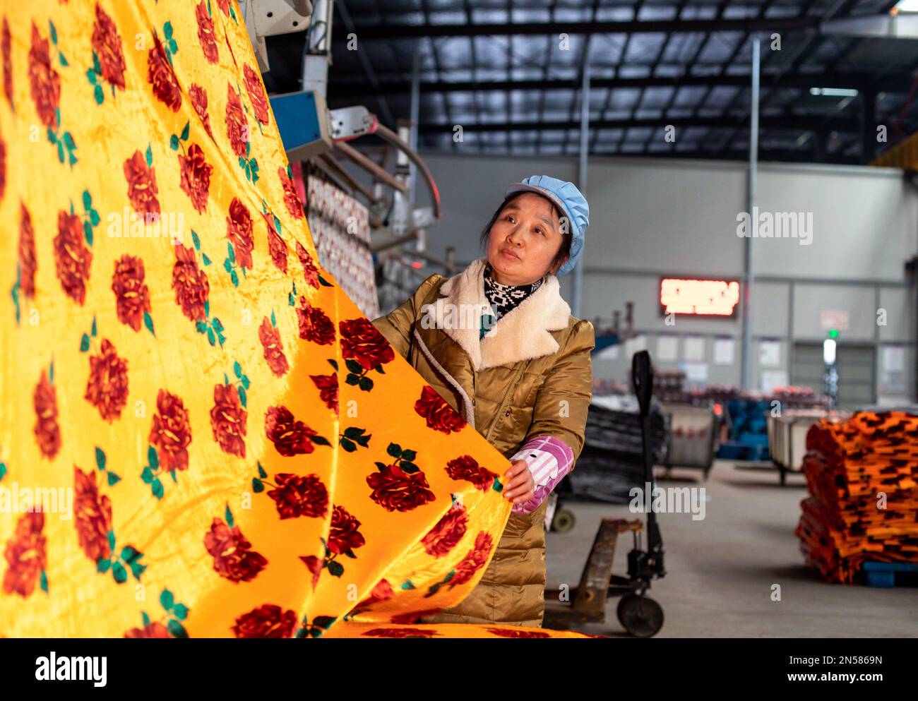 HAI'AN, CINA - 9 FEBBRAIO 2023 - Un lavoratore produce tessuti tessili per l'esportazione su una linea di produzione presso il laboratorio di produzione di Nantong Leyida Textile Foto Stock