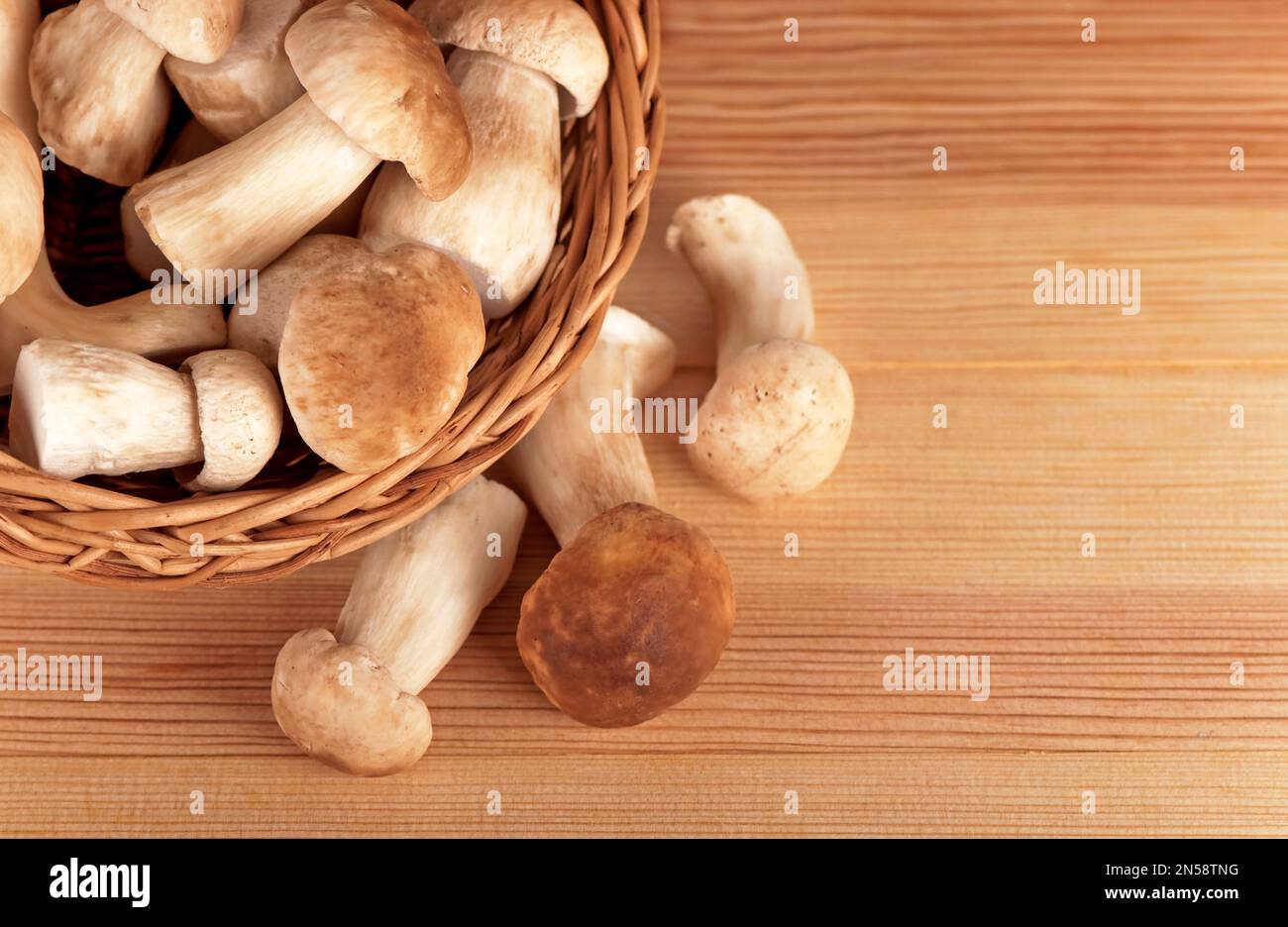 funghi bianchi crudi in cesto su tavola di legno Foto Stock